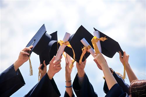 Students holding up graduation cap together in a circle Students holding up graduation cap together in a circle